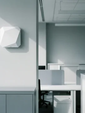 Witte draadloze toegangspunt gemonteerd op lichtgrijze muur in modern minimalistisch kantoor