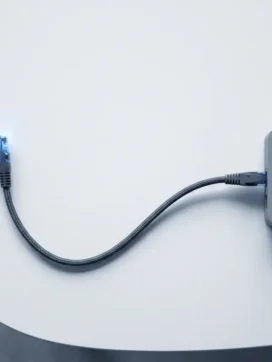 Ethernet-kabel met blauwe connector verbindt met moderne router op witte ondergrond, overhead perspectief
