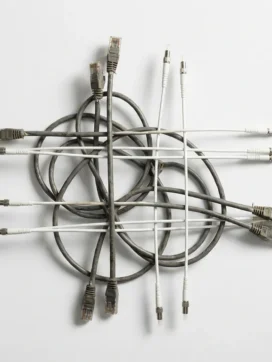 Verwarde grijze ethernetkabels en glanzende witte glasvezelkabels kruisen elkaar op wit oppervlak, overgang van oud naar nieuw