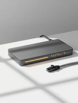 Moderne netwerkswitch met amber statuslampjes op wit bureau, ethernet kabel losgetrokken ernaast, minimale kantooromgeving