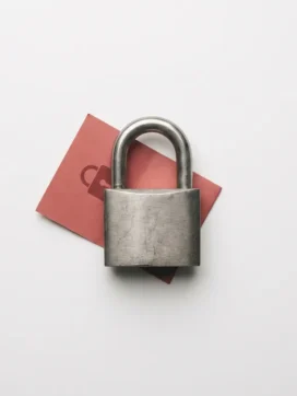 Zwaar stalen hangslot op wit oppervlak met gevouwen rode waarschuwingsbrief, minimalistische flatlay over veiligheid en naleving.