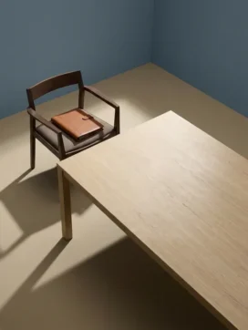 Houten bestuurdersstoel aan het hoofd van een minimalistische vergadertafel met een gesloten leren portfolio, zacht directioneel licht.